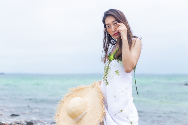 Giovani belle donne nel bianco con il cappello di paglia sulla spiaggia.