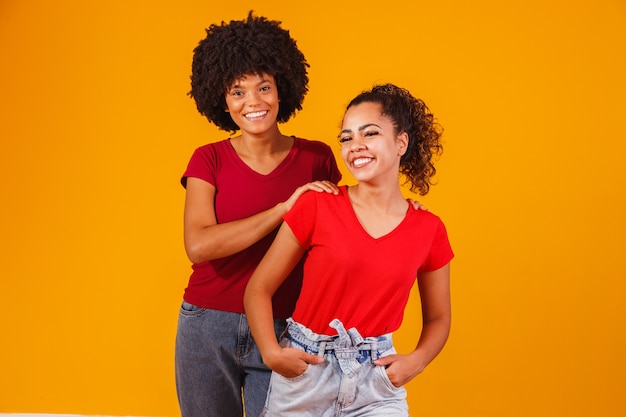 Giovani belle e felici amiche afro sorridenti alla telecamera.