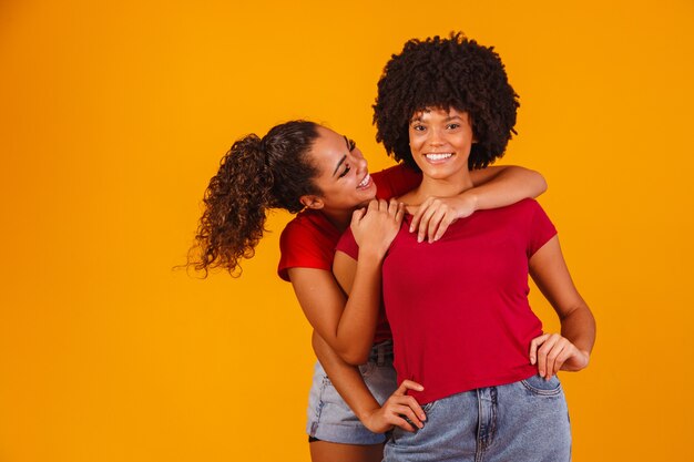 Giovani belle e felici amiche afro sorridenti alla telecamera.