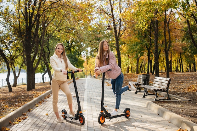 Giovani belle ragazze che guidano scooter elettrici