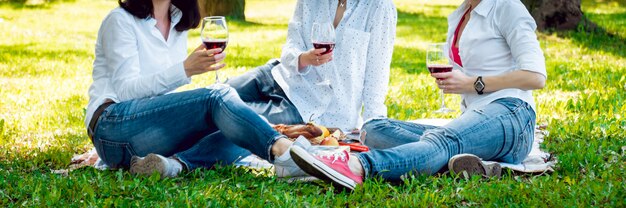 Giovani belle ragazze con bicchiere di vino rosso nel parco