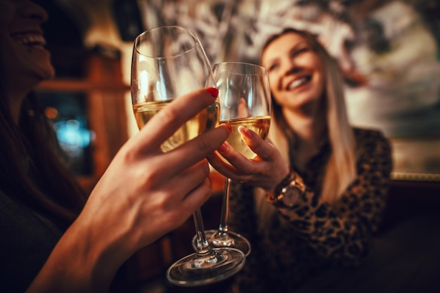 Giovani cari amici sorridenti sono seduti al bar, parlando, brindando e bevendo vino.