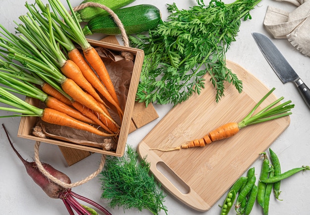 Giovani carote, zucchine, barbabietole e piselli su uno sfondo grigio. Cucinare un piatto di verdure.