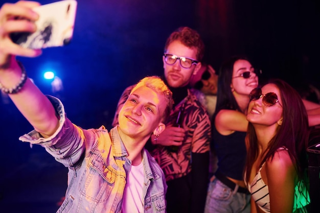 Giovani che fanno selfie in discoteca con luci laser colorate
