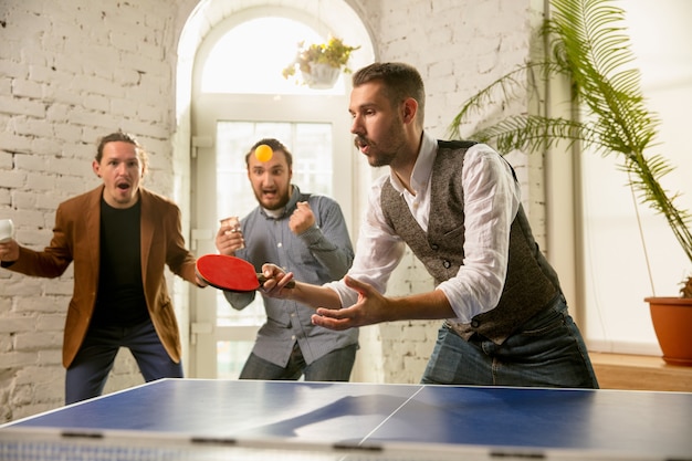 Giovani che giocano a ping pong sul posto di lavoro, divertendosi