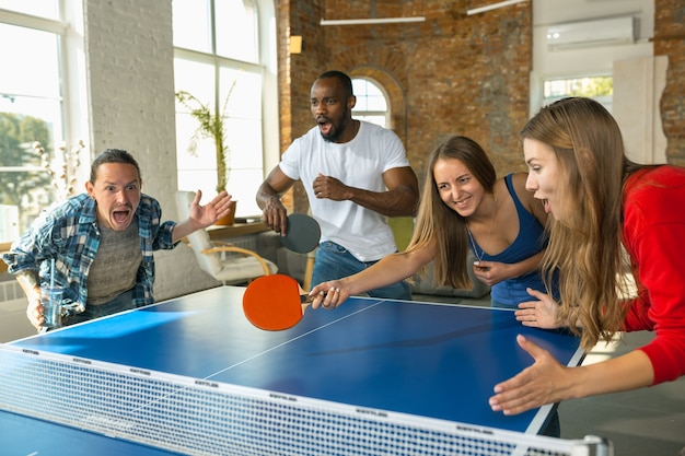 Giovani che giocano a ping pong sul posto di lavoro, divertendosi