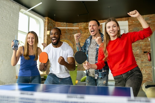 Giovani che giocano a ping pong sul posto di lavoro, divertendosi