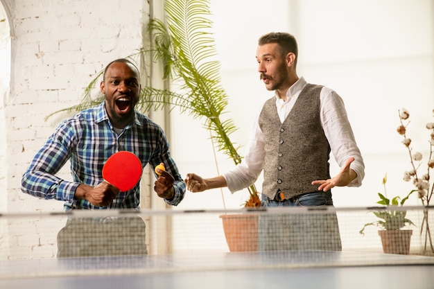 Giovani che giocano a ping pong sul posto di lavoro, divertendosi