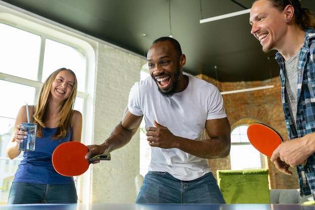 Giovani che giocano a ping pong sul posto di lavoro, divertendosi