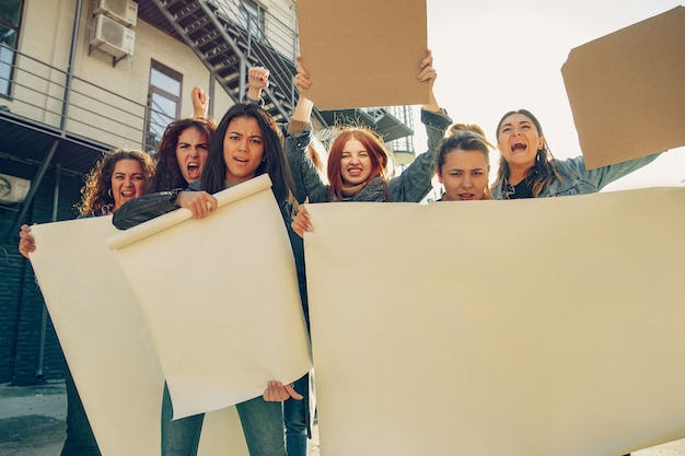 Giovani che protestano per i diritti e l'uguaglianza delle donne per strada. Le donne caucasiche si incontrano per problemi sul posto di lavoro, pressioni maschili, abusi domestici, molestie. Copyspace. Tenendo manifesti.