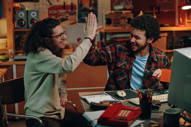 Giovani che si danno il cinque mentre sono seduti al tavolo in officina