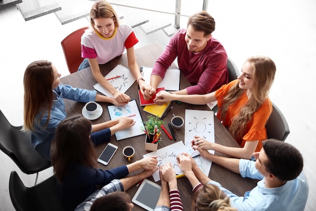 Giovani che si tengono per mano mentre lavorano al progetto in interni Concetto di unità