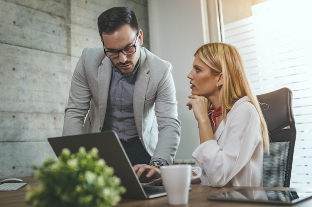 Giovani colleghi di lavoro stanno lavorando su un computer, analizzando il progetto e parlandone in ufficio.