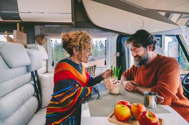 Giovani coppia matura godere della vita in un camper van motorhome insieme in attività di svago al chiuso vista della natura fuori dalla finestra felice viaggiatore persone uomo e donna all'interno di un furgone per le vacanze vacanze