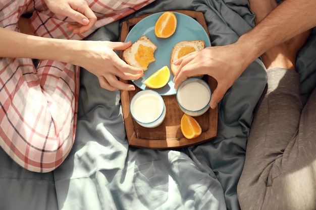 Giovani coppie adorabili che mangiano colazione sul letto