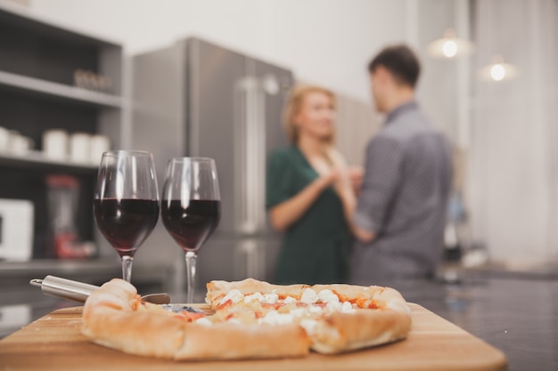 Giovani coppie adorabili che mangiano insieme pizza alla cucina