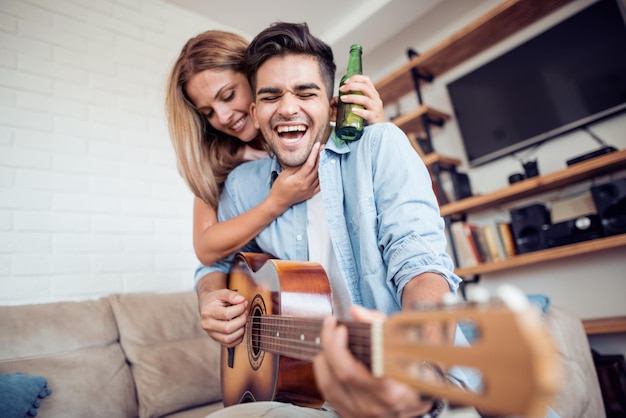 Giovani coppie adorabili che suonano la chitarra a casa