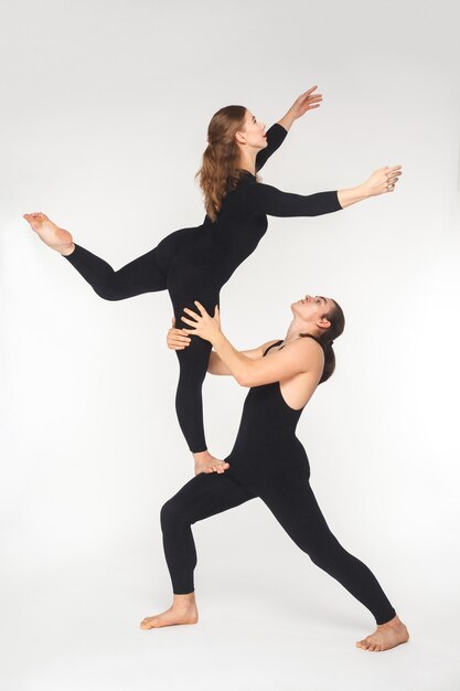 Giovani coppie adulte che fanno posa di acroyoga per esercitarsi nell'equilibrio. Studio girato, isolato su sfondo bianco