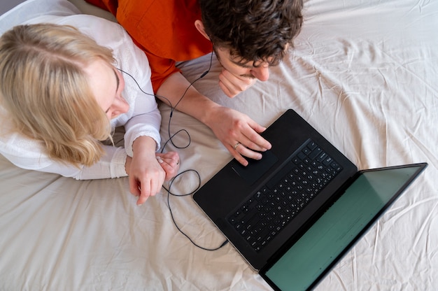 Giovani coppie adulte che per mezzo insieme del computer portatile e delle cuffie