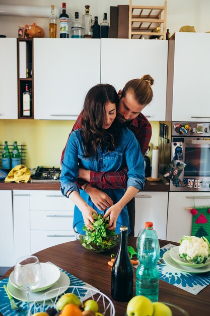 Giovani coppie affettuose che cucinano alimento in cucina a casa