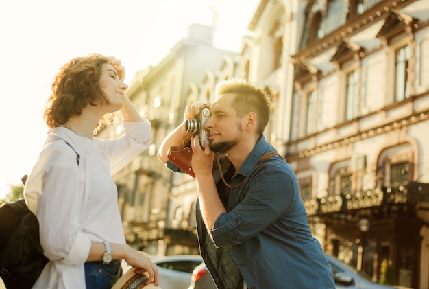 Giovani coppie allegre di hipster vengono fotografate con una fotocamera retrò mentre passeggiano per la città