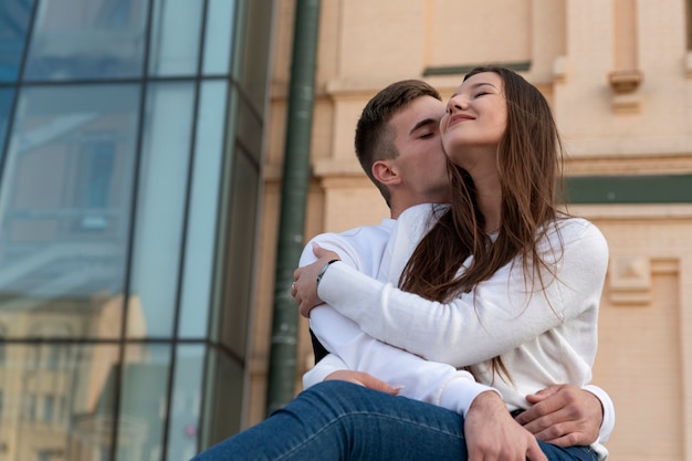 Giovani coppie amorose che abbracciano nella superficie dell'architettura urbana. Ragazzo che bacia la sua ragazza.