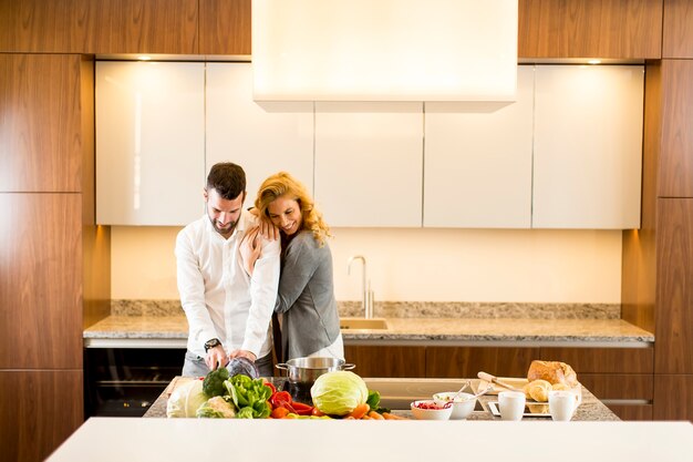 Giovani coppie amorose che preparano pasto gustoso in una cucina moderna