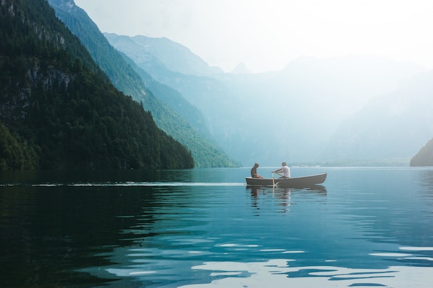 Giovani coppie amorose in barca nel lago. Data passeggiata uomo e donna in montagna alpina