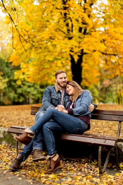 Giovani coppie amorose sulla panchina nel parco in autunno