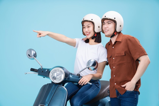 Giovani coppie asiatiche cavalcano scooter sullo sfondo
