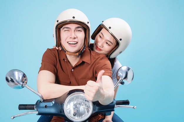 Giovani coppie asiatiche cavalcano scooter sullo sfondo