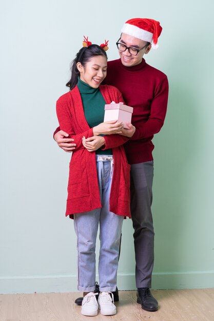 Giovani coppie asiatiche in posa su sfondo verde con concetto di natale