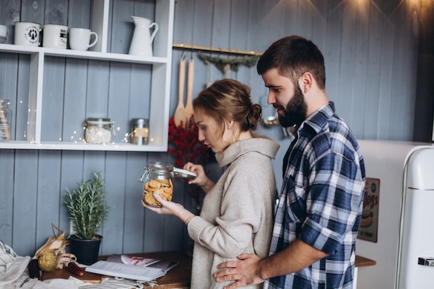 Giovani coppie caucasiche alla moda che cucinano, abbracciando nella cucina accogliente moderna. Felicità, libertà, concetto di famiglia