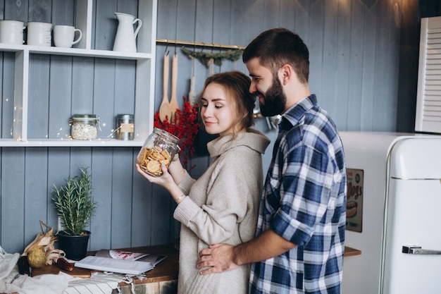 Giovani coppie caucasiche alla moda che cucinano, abbracciando nella cucina accogliente moderna. Felicità, libertà, concetto di famiglia