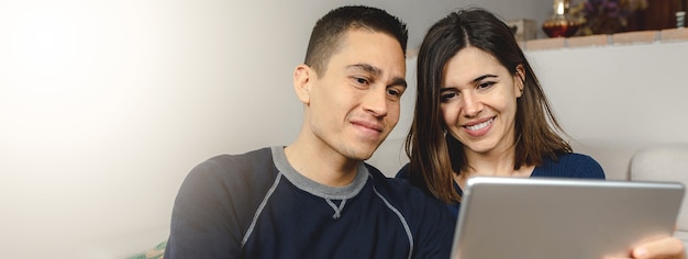 Giovani coppie caucasiche felici utilizzando computer tablet per una videochiamata.