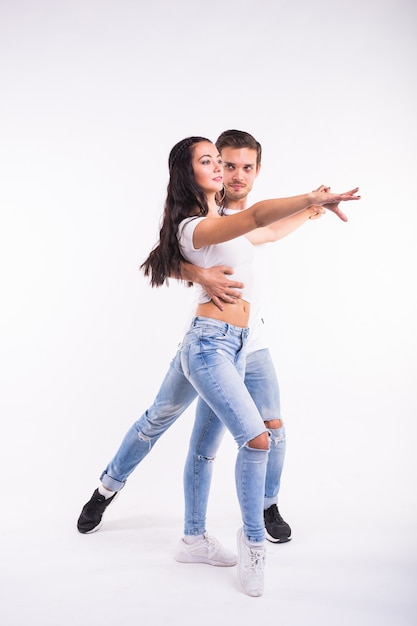 Giovani coppie che ballano bachata di ballo sociale, merengue, salsa, kizomba. Due pose di eleganza sulla stanza bianca