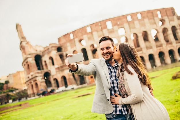 Giovani coppie che catturano selfie davanti al Colosseo a Roma, Italia