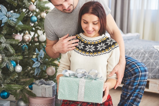 Giovani coppie che celebrano il Natale. Un uomo improvvisamente ha presentato un regalo a sua moglie. Il concetto di felicità e benessere familiare