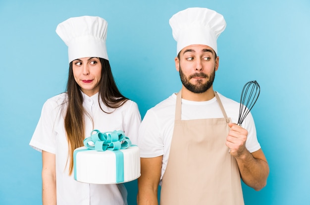 Giovani coppie che cucinano una torta che morde insieme le unghie, nervose e molto ansiose.