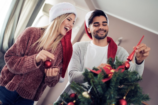 Giovani coppie che decorano un albero di Natale