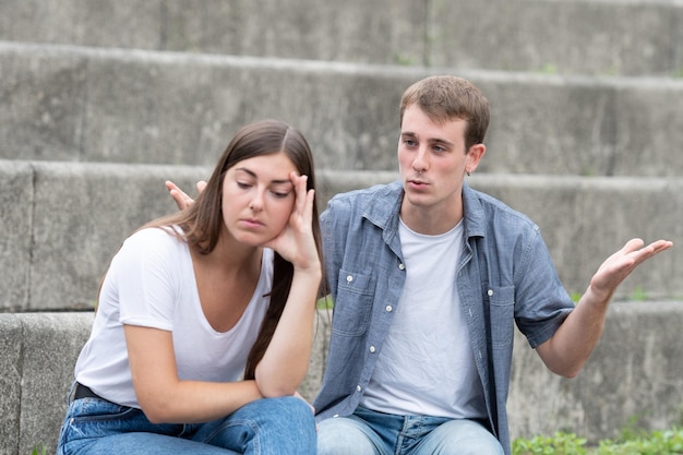 Giovani coppie che discutono all'aperto mentre la donna è disperata. Concetto di relazioni cattive e tossiche