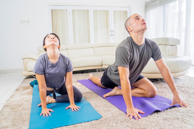 Giovani coppie che fanno esercizio di yoga a casa