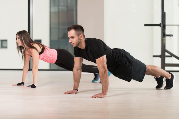 Giovani coppie che fanno flessioni in palestra