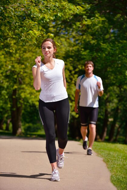 Giovani coppie che fanno jogging nel parco al mattino. Salute e fitness.