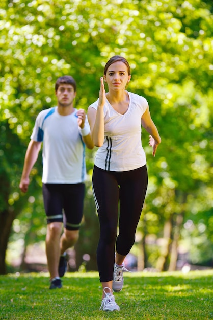 Giovani coppie che fanno jogging nel parco al mattino. Salute e fitness.