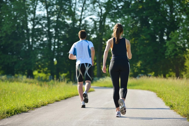 Giovani coppie che fanno jogging nel parco al mattino. Salute e fitness.