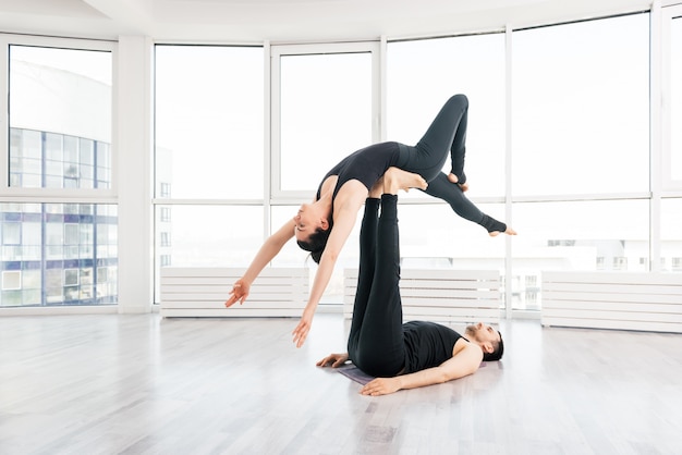 Giovani coppie che fanno yoga di acro negli accoppiamenti allo studio