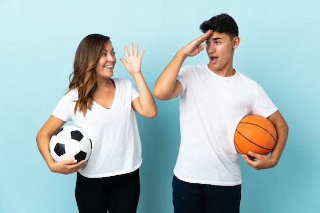 Giovani coppie che giocano a calcio e basket in blu con espressione facciale sorpresa e scioccata