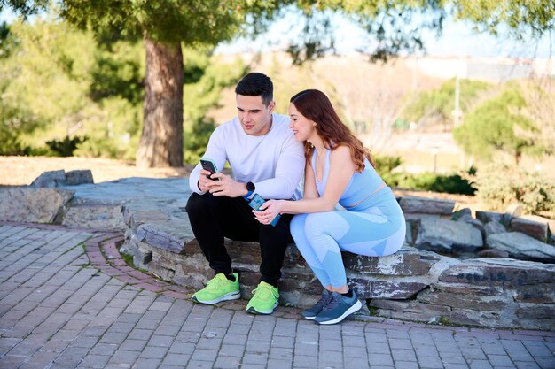 Giovani coppie che guardano contenuti online su uno smartphone seduto in un parco