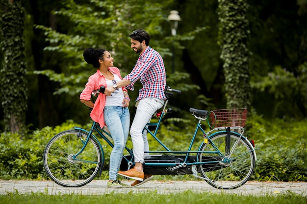 Giovani coppie che guidano sulla bicicletta in tandem